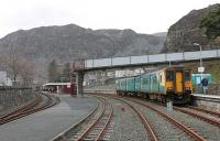 The 'new' central station and interchange in Blaenau Ffestiniog celebrates its 30th anniversary in 2012. This view from the boarded crossing looks west and just beyond the far bridge the two railways diverge. The Ffestiniog narrow gauge trains swing left to head down to Porthmadog while the Conwy Valley line trains pass the old LNWR station (closed in 1982) and turn sharp right to go north past the slate tips and into the two mile long tunnel to Roman Bridge. 150277 waits to return to Llandudno.<br><br>[Mark Bartlett 01/12/2011]