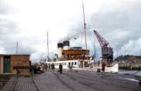 Scene on the south side of Ayr harbour in September 1955 with TS <I>Duchess of Hamilton</I> berthed in her usual place. Built for the Caledonian Steam Packet Company by Harland and Wolff at Govan, she was the regular Ayr steamer and had been fitted with a bow rudder (the wheel is just visible on the foredeck) to assist movements at Ayr, which was difficult to enter under certain conditions. The railway sidings here were reached from the goods station located to the north of the harbour via a now-dismantled bridge, the piers of which still stand in the river. [See image 45697]<br><br>[A Snapper (Courtesy Bruce McCartney) 09/09/1955]