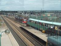 Looking towards Rotherham from the glass footbridge at Meadowhall as Sheffield Supertram 114 arrives at the interchange. The line of white poles denotes the tram route which turns sharp right just in front of the M1 Tinsley Viaduct to loop back towards the city centre.<br><br>[Mark Bartlett 19/03/2011]