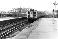 A class 423 emu arrives at Clapham Junction in 1981. Squatting over the western tracks is the 1912 Clapham Junction 'A' box, which consisted of a series of wooden sheds perched on a bowstring girder bridge. The frame once supported a 40 ton steel canopy, erected as air raid protection during WWII. This led to a partial collapse in May 1965, resulting in suspension of services while the canopy was removed. Clapham Junction 'A' signal box closed in 1989 [see image 5687].<br><br>[John Furnevel 18/09/1981]