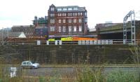 A Kingmoor - Chirk log train about to pass below Victoria Viaduct on the northern approach to Carlisle station on 26 January 2012. A class 66 locomotive, sporting the subtle hues of 'Colas Rail Freight', leads the way.<br><br>[Bruce McCartney 26/01/2012]