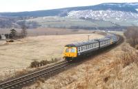 A DMU westbound past the site of Orton station on a March afternoon in 1979. The River Spey bridge stands in the background, with the trackbed of the long gone line from Orton to Rothes to the right [see image 25801]. <br><br>[Peter Todd 30/03/1979]