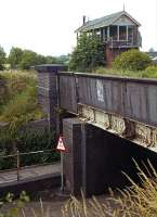 Immediately beyond the exit from Maldon East station was a level crossing on a busy main road (the B1018), and beyond that the station signal box. At times of freight shunting, the gates could be shut some considerable time, and it was necessary to provide an underpass for pedestrians and light traffic. Headroom was only 9 feet. This view, recorded 12 years after final closure, shows the underpass, overbridge and derelict signal box before all was swept away for a new roundabout. [See image 26158]<br><br>[Mark Dufton 15/07/1978]