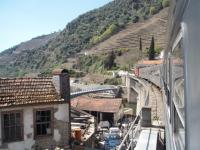 The whistling English Electric exhaust of the CP1400 (EE Type 1) echoes off the steep hillsides and the houses close to the line as it accelerates its three coaches away from Pinhao station. The train is just crossing a tributary of the River Douro on its way down to Porto. Later in the year the hillside terraces will be covered in vines in this Port producing region.<br><br>[Mark Bartlett 20/03/2008]