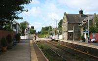 Platform view west at Bare Lane station, looking towards Morecambe on 11 August 2009. The signalbox stands on the left with the level crossing beyond.<br><br>[John McIntyre 11/08/2009]
