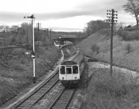 The Wennington signalman has been quick to return his down (?) starter to danger as a Leeds - Morecambe DMU accelerates away from the station during the early evening of Saturday 24th April 1976. Running off to the right is the trackbed of the direct line to Lancaster, closed in 1966.<br><br>[Bill Jamieson 24/04/1976]