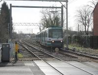 Metrolink 1006 leads a four car formation off the double track section from Altrincham and over the level crossing into Navigation Road. At the same point the Network Rail single track branches out to two lines again but on this side the overhead catenary was removed in 1992. With a tram in each direction every six minutes plus passenger and freight trains the barriers at this crossing are kept very busy.<br><br>[Mark Bartlett 08/03/2012]