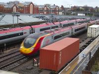 A Pendolino stands at Tamworth Low Level platform 1 with the 16.57 London Euston - Glasgow Central on 4 April 2012. Meantime a loaded Freightliner intermodal service headed by 66557 runs south through platform 2, just as a southbound Pendolino passes on the centre road at maximum line speed.<br><br>[David Pesterfield 04/04/2012]