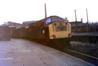 Class 40 No. 354 leads an evening van train standing in the parcels' siding at Accrington in 1970, shortly before this traffic ceased altogether. The train is in the old Bury line platform (closed 1966), but will have reversed into here and will go forward to continue its journey towards Colne. To the right of the loco old railway buildings stand in the middle of what had been a triangular junction - but not for much longer. Behind the train part of the huge Howard and Bullough factory complex can be seen. This company exported textile machinery all over the world and in 1953, to celebrate its centenary, hired 14 special trains to take the entire workforce from Accrington to Blackpool. By the time this picture was taken the factory was part of the Platt group but closed in the early 1980s and has since been demolished. In 2010 a brand new station building was built just about where the Class 40 is idling. [See image 32139].<br><br>[Mark Bartlett //1970]