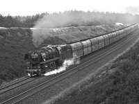 Oil-fired 2-10-0 No. 043 606 heads south through the cutting at Lathen on the Rheine - Emden line in 1975. The line was famous for the double-headed trains conveying imported iron ore from the docks at Emden but the bogie hoppers depicted here appear to be empty and had probably conveyed export coal to Emden on their outward journey.<br><br>[Bill Jamieson 10/05/1975]