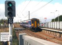 The 10.18 Glasgow Central - Edinburgh Waverley runs over the level crossing into Kirknewton station on 17 April 2012. Bottom left is the button used by drivers of westbound stopping services to activate the crossing barriers when the train is ready to leave.<br><br>[John Furnevel 17/04/2012]