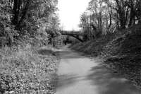 Taken from the west of the site of the island platform at Alloway in May 2012 looking to Alloway Junction. The cutting is partially filled on the right by an access ramp for the cycle path. The footbridge is new and the road bridge in the background, built to serve a new housing development, straddles the mid-point of the old station site.<br><br>[Colin Miller 05/05/2012]