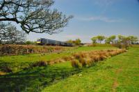 A westbound train passes the remains of the Aberdeenshire Canal east of Pitmedden in May 2012. The GNSR is often described as being laid on the route of the canal but a canal meanders far more than a railway and so a number of curved sections, such as this one, still survive.<br><br>[Ewan Crawford 23/05/2012]