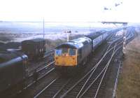 Token exchange at Georgemas Junction on a grey day in late summer 1971. The Wick portion of a southbound train is arriving from the east, while the Thurso branch locomotive waits at the head of its coaches ready to back on to the Wick portion once it has drawn to a halt at the southbound platform.<br><br>[Frank Spaven Collection (Courtesy David Spaven) //1971]