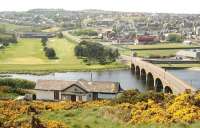 View west over the River Deveron towards the town of Banff, Aberdeenshire, showing Banff Bridge, which carries the A98. Across the river on the left stands Duff House Royal Golf Club, while emerging from the broom on this side of the divide is the former Banff Bridge station, now a private residence. [See image 39392]<br><br>[John Furnevel 23/05/2012]