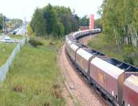 Road and rail approaches to Alloa from the east in May 2012. To the left, the A907 runs toward the town centre beyond Clackmannan Road roundabout. On the right a train of coal empties from Longannet heading back to Hunterston passes the rear of the town's fire station.<br><br>[John Furnevel 09/05/2012]