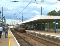 A Class 365 EMU arrives at Ely on 4 July 2012 with a Kings Lynn to London Kings Cross service as HGVs start to move over the level crossing at the north end of the station. Although there is an underpass for cars and small vans, larger vehicles have to use the crossing which can lead to significant delays as rail traffic at times can be fairly busy.<br><br>[John McIntyre 04/07/2012]