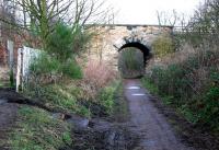 The site of Ormiston Station in December 2004, looking east along the remains of the overgrown platform towards the road bridge carrying the B6371. Just beyond the bridge was the junction for the Macmerry and Gifford branches. The line closed completely in 1965.  [See image 22414].<br><br>[John Furnevel 05/12/2004]