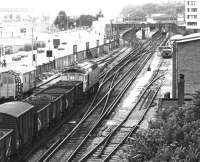 A westbound mixed freight approaching Southampton Central in July 1981 behind a class 33 locomotive, with passenger trains occupying both up platforms.<br><br>[John Furnevel 06/07/1981]