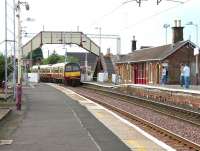 An early evening train from Helensburgh entering Cardross station over the level crossing on a warm summer evening in July 2005. Note the significant drop in the height of the eastbound platform beyond the station building. [See image 32216] <br><br>[John Furnevel 27/07/2005]