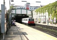 Train for Wimbledon arriving at West Brompton District Line platforms in the shadow of Earls Court Arena on a sunny afternoon in July 2005.<br><br>[John Furnevel 22/07/2005]