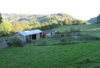 The line of trees behind the farm building is the track of the Severn  and Wye climbing from Lydbrook Junction towards the Forest of Dean. The Lydbook valley is to the right of the picture. Under the trees are  piles of large dressed stones - the remains of Lydbrook Viaduct. The  farm was sold shortly after this picture was taken in 2004 and there is now a large house on the site. The land is still accessible from a public path from the valley road. (Immediately behind the camera lies one of the few visible sections of Offa's Dyke).<br><br>[John Thorn 13/10/2004]