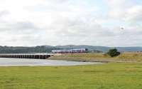 The tide is just ebbing as TPE 185142 comes off the refurbished Kent Estuary viaduct and onto the steeply cambered embankment that leads into Arnside station. The train is a Barrow-in-Furness to Manchester Airport service.<br><br>[Mark Bartlett 03/09/2012]