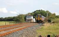 Track level view of Arnside signal box as 153304 leaves the station heading for Barrow-in-Furness with a Northern stopping service on 3 September. To the left of the box the embankment that carried the long closed line to Hincaster Junction alongside the Kent Estuary can be seen.<br><br>[Mark Bartlett 03/09/2012]