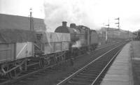 An up freight of covered mineral wagons is held at signals alongside Hellifield station on a damp and overcast February day in 1965. The locomotive is leaky Fowler ex-Midland 4F 0-6-0 no 44462 off Skipton shed.<br><br>[K A Gray 13/02/1965]