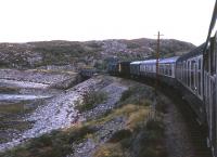 Just out of Kyle, a Class 24-hauled train for Inverness hugs the shoreline at Erbusaig in Summer 1974. [With thanks to all who responded to this query.<br><br>[David Spaven //1974]