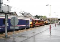 A very wet Thursday morning at Carstairs in May 2007 as EWS 90026 runs through the station off the Edinburgh line with empty stock of the Caledonian Sleeper heading for Polmadie. The train is about to overtake 'Thunderbird' 57316 <I>Fab1</I> held in the loop with a northbound freight.<br><br>[John Furnevel 17/05/2007]