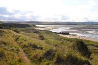 Taken from the embankment of the old 3ft gauge railway from Kittling Hill whinstone quarry to Budle pier, Bamburgh. Trackbed in foreground, with the remains of Budle pier in the middle distance. A zig - zag existed between the embankment level and pier level to allow locomotives and trucks access. The zig - zag is now largely obscured by dunes and vegetation. Small coasting steamers would enter Budle bay to load stone at the pier. [See image 40434] <br><br>[Brian Taylor 22/09/2012]