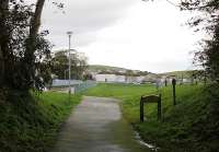 The site of the Campbeltown and Machrihanish carriage and loco sheds, now an open space, was just at the top of the steep bank from the quayside. This is the modern day view looking west from the end of the deep cutting with its trackbed footpath. The houses in the distance are built over the old line. [See image 33469] for a map showing the cutting and sheds in 1921.<br><br>[Mark Bartlett 13/10/2012]