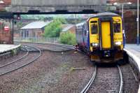 Downpour at Dumfries on 28 June 2012 as the 13.48 Class 156 for Glasgow pulls into the platform. Some of the buildings in the old goods yard are visible through the bridge [see image 19224]. <br><br>[Colin Miller 28/06/2012]