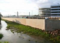 The massive retaining wall now running alongside the Gogar Burn within Edinburgh Airport. Beyond the wall work is well advanced on the creation of the new tram terminus [see image 40726]. View south on 21 October 2012 with the multi-storey car park on the right beyond Jubilee Road. Behind the camera is the main runway below which the Burn is routed before meeting the River Almond on the northern perimeter of the airport. <br><br>[John Furnevel 21/10/2012]