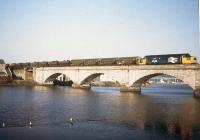 One of the few occasions on which coal moved south on the Far North Line. Some of the 13 HEA hopper wagons of imported coal - a contract secured to rail by the photographer's son as BR Speedlink Coal manager for Scotland - conveyed on a southbound freight from Invergordon on 12th February 1986 are seen here on the original Ness Bridge in Inverness.<br><br>[Frank Spaven Collection (Courtesy David Spaven) 12/02/1986]