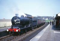 Class J37 0-6-0 no 64602 at the head of a southbound railtour from Dundee stands at Anstruther station on the Fife Coast line in the early 1960s. Part of the tower and flagpole of Waid Academy can be seen beyond the station canopy on the right. <br><br>[Robin Barbour Collection (Courtesy Bruce McCartney) //]