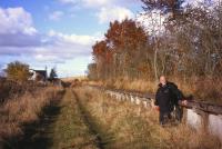 Railscot contributor David Spaven rests against the surviving Up platform at Heriot on a 'Waverley Route Wander' on 26th October 2012. Advance engineering works to shift utilities in advance of the Borders Railway works can just be glimpsed in the distance.<br><br>[Bill Jamieson 26/10/2012]