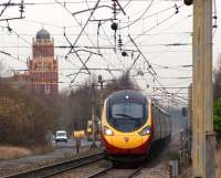 A southbound Pendolino passes the site of Coppull station on 23 November 2012. To the west of the once 4 track railway stands the Coppull Spinning Mill which has found new use as a series of retail and office units under the auspices of Lancashire Enterprises.<br><br>[John McIntyre 23/11/2012]