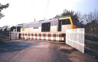 A Redmire - Teesside limestone train runs east over Wensley level crossing in March 1993. The former Wensley Station is just off picture to the left. Locomotive 60038 <I>'Bidean Nam Bian'</I> is in BR Trainload Metals livery. [See image 40138]<br><br>[Ian Dinmore /03/1993]