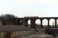 A class 141 Pacer in West Yorkshire PTE red livery runs across the lofty Denby Dale viaduct in February 1991, before entering the station out of view on the left. <br><br>[David Pesterfield 09/02/1991]