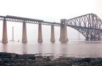 A northbound 6-car DMU on the Forth Bridge on 16th July 1961, with the towers of the under-construction road bridge visible through the mist. The DMU is about to pass a class 08 with a 'painters train' [see image 27855].<br><br>[Frank Spaven Collection (Courtesy David Spaven) 16/07/1961]