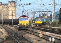 Platform view from the east end of Newcastle Central in July 2004. EWS 66229 is approaching with a coal train from the north with a DMU coming off the High Level Bridge. The Castle Keep stands on the left, while the north end of the Tyne Bridge can be seen in the right background.<br><br>[John Furnevel 06/07/2004]