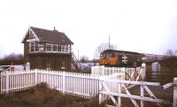 A diverted ECML electric service bound for Kings Cross is dragged by a class 47 over the level crossing at St James Deeping, Lincolnshire, in January 1991. The location is approximately 10 miles north east of Peterborough.<br><br>[Ian Dinmore 27/01/1991]