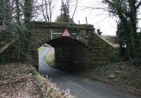 <I>Half a bridge is better than none</I>. Just east of the old Kirkby Lonsdale station, on the Low Gill to Clapham line, is the village of Cowan Bridge where this bridge carried the railway over the lane to Leck. With the embankment having been removed many years ago it is surprising that the low bridge hasn't gone too but it still straddles the road, 47 years after it carried its last train. Map Ref SD636765. <br><br>[Mark Bartlett 20/01/2013]