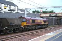 EWS 66203 is held in Carstairs station down loop with a train of coal empties, early on 11 July 2006. Above the wall on Strawfrank Road the Station Hotel is displaying a 'for sale' sign.<br><br>[John Furnevel 11/07/2006]