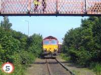 A hot day at Leith South in June 2006 as EWS 66205 draws slowly to a halt on the approach to Seafield level crossing. The trainload of imported Russian coal from Leith Docks is destined for Cockenzie power station. The two gentlemen on the footbridge are awaiting radio clearance before opening the crossing gates. <br><br>[John Furnevel 07/06/2006]