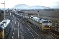 Brush Type 4 No 1765 eases the 13.58 Bathgate Upper to Ripple Lane empty Cartic 4s onto the Monktonall Junction line at Niddrie West in April 1970. Standing on the left is BR Sulzer Type 2 No 5067, the section ahead no doubt being occupied by another train - by 1970, the next open signalbox on the Sub was Morningside Road.<br><br>[Bill Jamieson 15/04/1970]