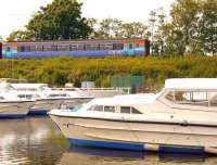 A 'Bittern Line' train passing Boats moored at Hoveton in 2006.<br><br>[Ian Dinmore //2006]