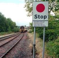 The morning train from Wick and Thurso runs over the A836 level crossing and into Lairg station during its journey south to Inverness in the autumn of 2001.<br><br>[John Furnevel 09/09/2001]